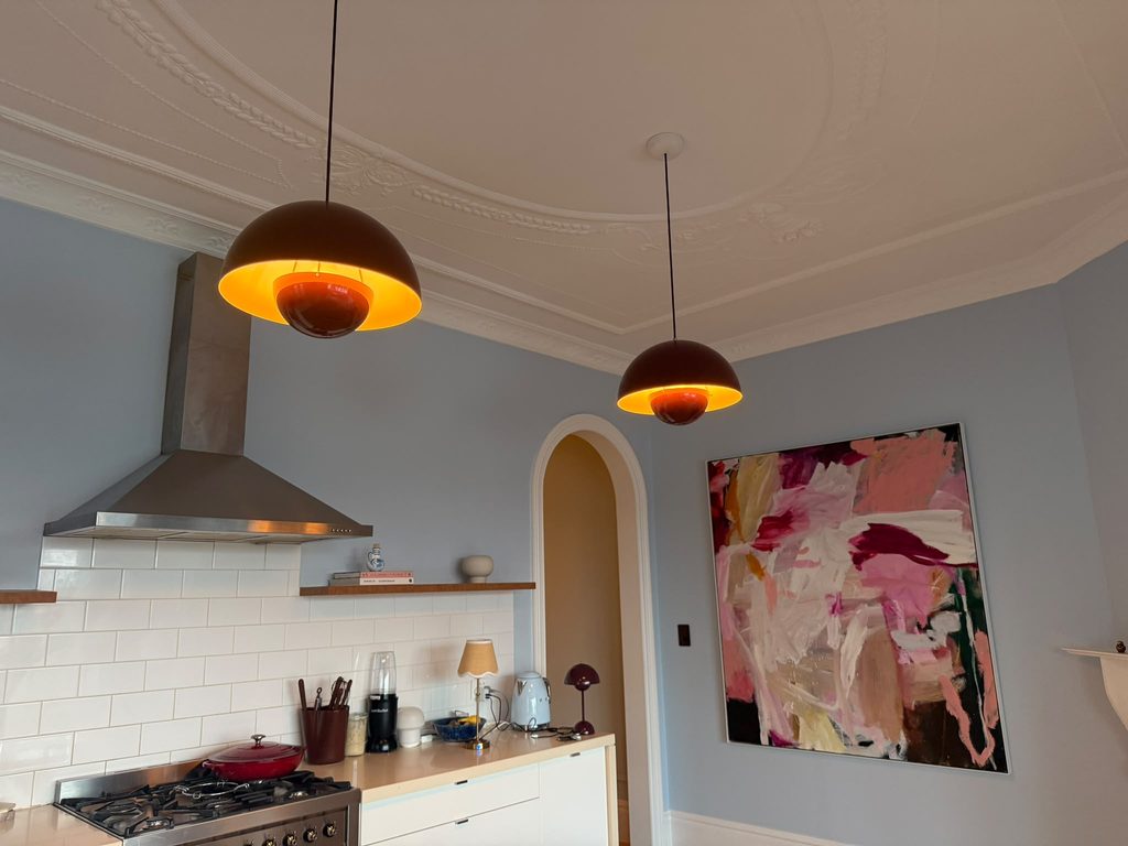 A kitchen with two dome pendant lights glowing above the bench, under an ornate plaster ceiling