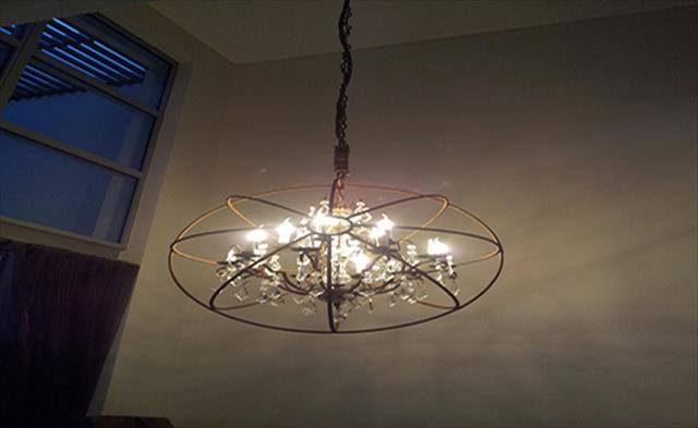 A ring chandelier with exposed bulbs lit in a living room