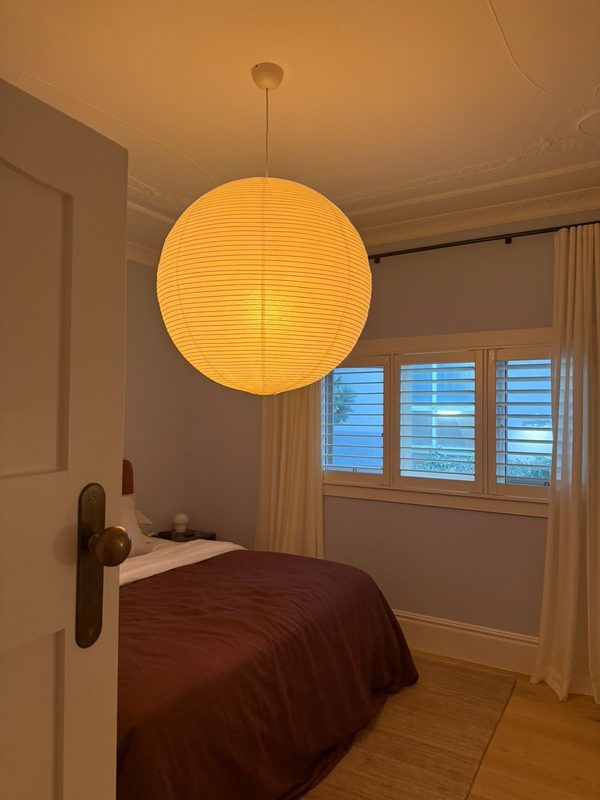 A large paper lantern pendant lit above a bed