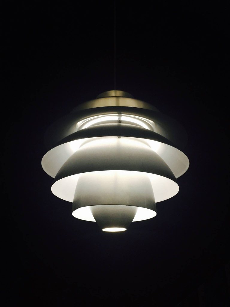A white layered pendant light glowing in a dark room