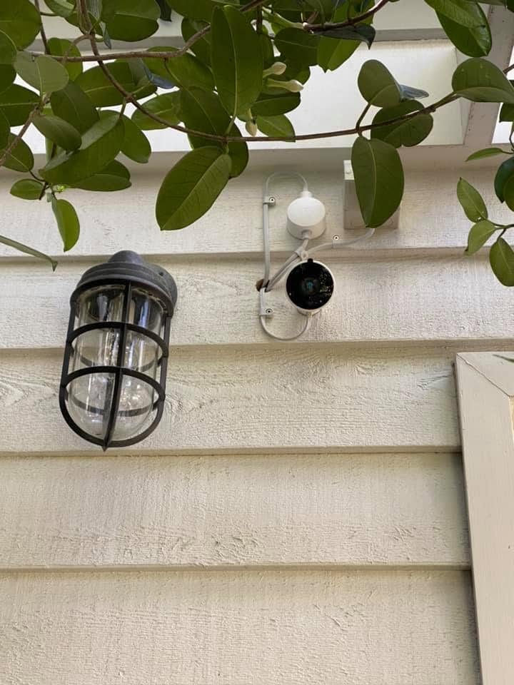 A security camera beside an outdoor wall light