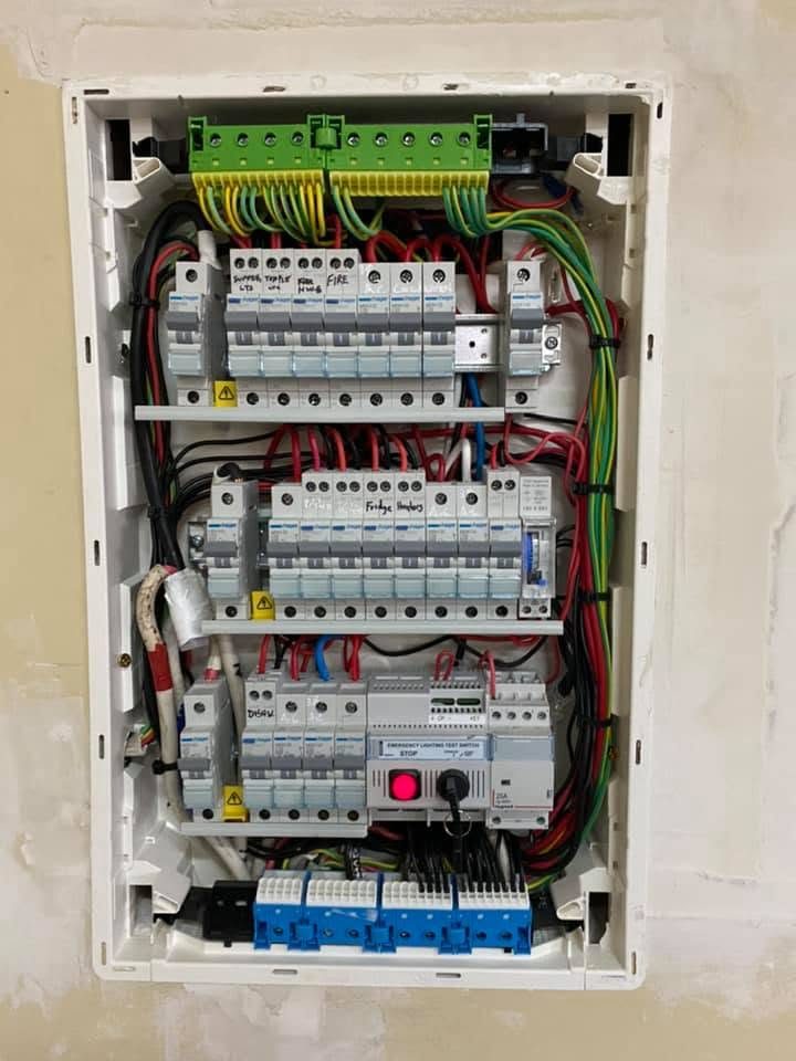A new switchboard with its cover off, rows of circuit breakers and safety switches wired in